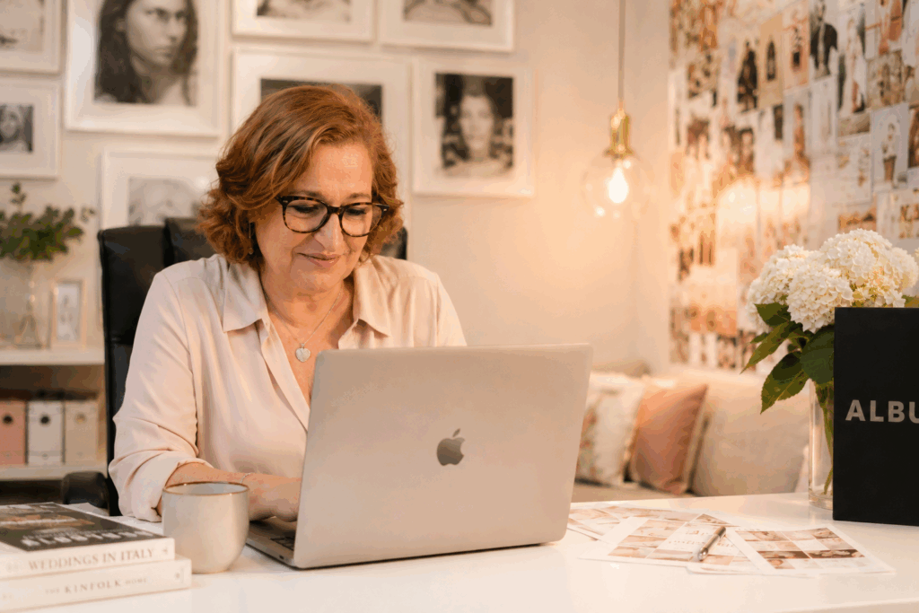 Daniela Ferrara smiling while working at her laptop in her wedding planning studio.